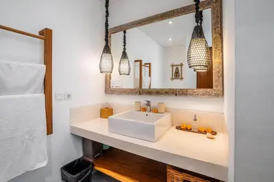a bathroom with a white sink and a mirror at Athos Villa by iBali Management in Seminyak