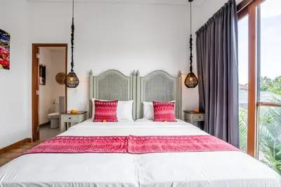 a bedroom with a large white bed with pink pillows at Athos Villa by iBali Management in Seminyak