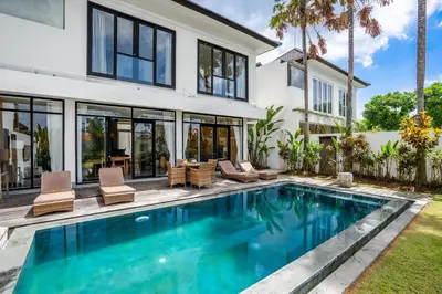 a swimming pool in front of a house at Athos Villa by iBali Management in Seminyak