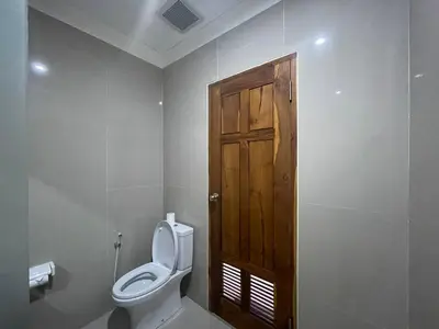 a bathroom with a toilet and a wooden door at Kusuma Coliving & Villas in Canggu
