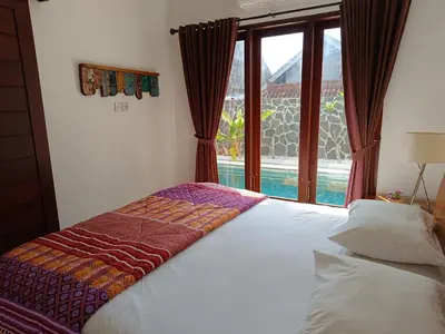 a bedroom with a bed and a window with a view at Casa Dijaweqo in Jimbaran