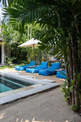 a pool with blue pillows and an umbrella next to it at Villa Malya 5 bedrooms Seminyak in Seminyak