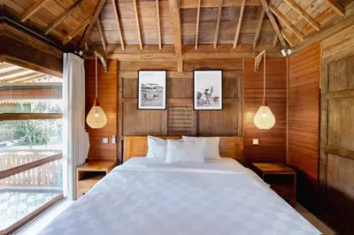 a bedroom with a large bed with wooden walls at Bale Bali Batubelig by ARM Hospitality in Canggu