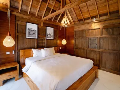 a bedroom with a bed in a wooden room at Bale Bali Batubelig by ARM Hospitality in Canggu