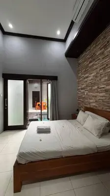 a bedroom with a large bed with a brick wall at MOOvilla 1 Seminyak, Bali in Umalas