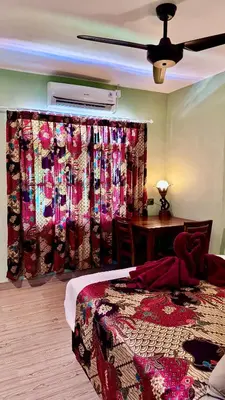 a bedroom with a bed and a table and curtains at Ellenbrook Rooms 18 by Mulia Cottage in Seminyak