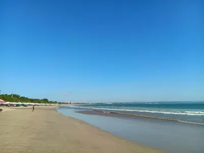 a beach with people on the sand and the ocean at Ellenbrook Rooms 18 by Mulia Cottage in Seminyak