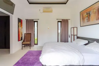a bedroom with a large white bed and a chair at Villa with private pool in Nusa Dua in Nusa Dua
