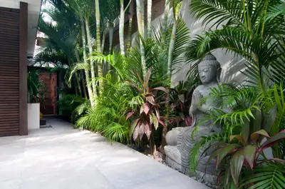 a statue in the middle of a courtyard with plants at 5BR Villa Sabtu - Minggu Villas Seminyak in Seminyak