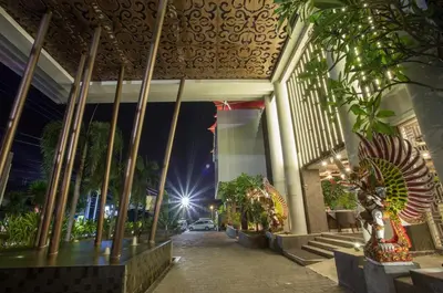 a building with columns and plants on a street at night at The Lerina Hotel Nusa Dua in Nusa Dua