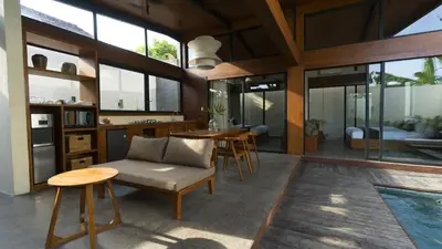 a living room with a table and chairs and a pool at Rarama Teba Villa in Umalas