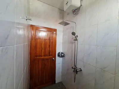 a bathroom with a shower and a wooden door at Shin In Bali in Kuta