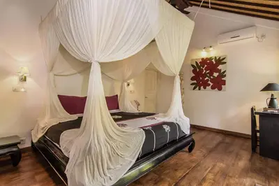 a bedroom with a canopy bed with white curtains at Villa Kija in Seminyak