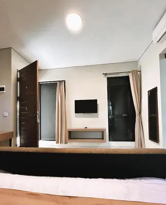 a bedroom with a large bed and a television at Nawasena Suites in Sanur