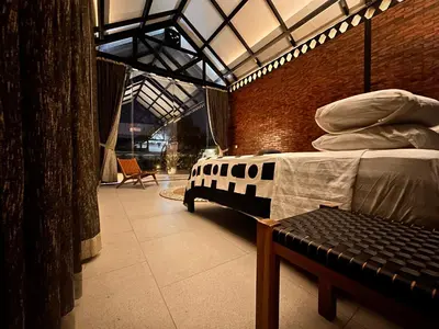 a room with a bed and a bench in it at The Edge by Anima in Kerobokan