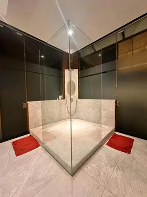 a glass shower in a room with red mats at The Edge by Anima in Kerobokan