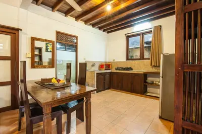 a kitchen with a wooden table and a refrigerator at 6-BR Garden Legian Villa 5-Min Walk to Beach and Shops Bali in Seminyak