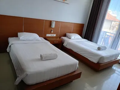 two beds in a hotel room with a window at Ronta Bungalows in Legian