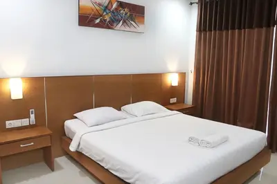a bedroom with a large bed with white sheets at Ronta Bungalows in Legian