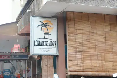 a sign on the side of a building with a palm tree at Ronta Bungalows in Legian