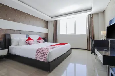 a bedroom with a large bed and a television at Townhouse Oak Denpasar at Mahendradatta in Denpasar