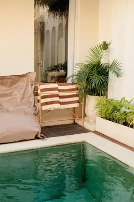 a house with a swimming pool and a chair and plants at Amethyst Villa Seminyak in Seminyak