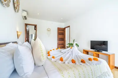 a bedroom with a white bed with orange pillows at Villa Gea by JB Villas in Seminyak