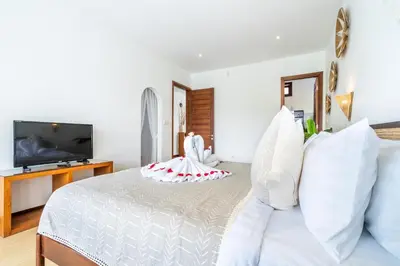 a bedroom with a white bed with white pillows at Villa Gea by JB Villas in Seminyak
