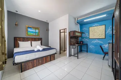 a bedroom with a bed and a blue wall at Senyum Bali Inn 1BR Sanur in Sanur