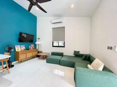 a living room with a green couch and a tv at Villa EM Umalas by Satran Villa in Kerobokan