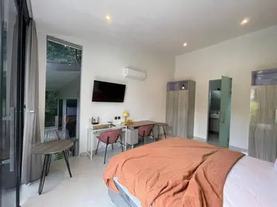 a bedroom with a bed and a table and a kitchen at Villa EM Umalas by Satran Villa in Kerobokan