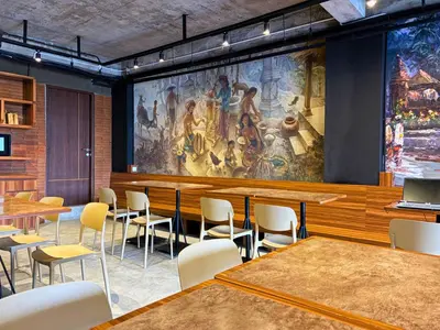 a room with tables and chairs and a large painting on the wall at Althia Private Capsule Quarters in Badung