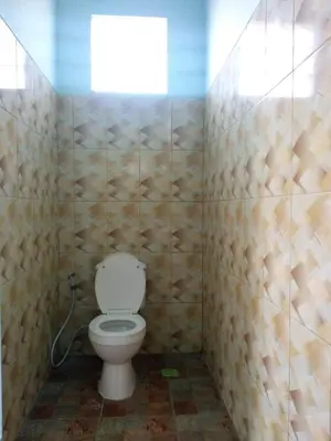 a bathroom with a toilet in a room with tiled walls at Bcoss Stay in Jimbaran