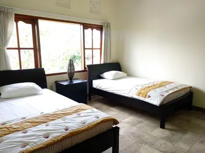 two beds in a room with a window at Bcoss Stay in Jimbaran