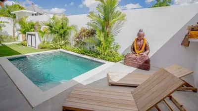 a buddha statue sitting next to a swimming pool at Villa La madrina in Kerobokan