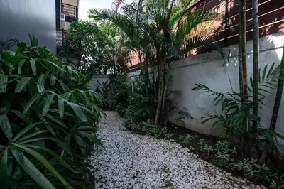 a garden with palm trees and plants next to a building at Bali Huis Villa in Seminyak