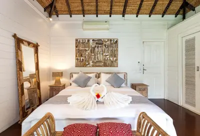 a bedroom with a large bed with two chairs at Palm Merah Villa in Umalas