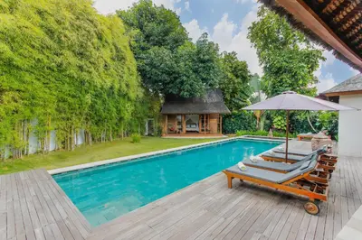 a swimming pool with two lounge chairs and an umbrella at Villa Charlie Seminyak in Badung