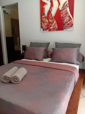 a bed with two towels on it with a painting on the wall at J & J villa Seminyak in Seminyak