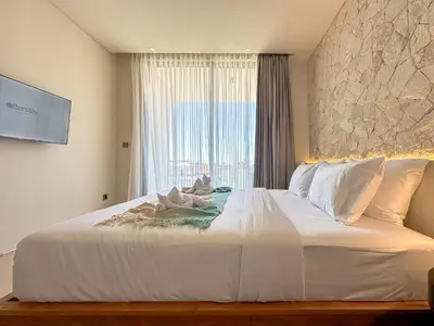a bedroom with a large white bed with a window at Saint Cloud Villa Umalas in Canggu