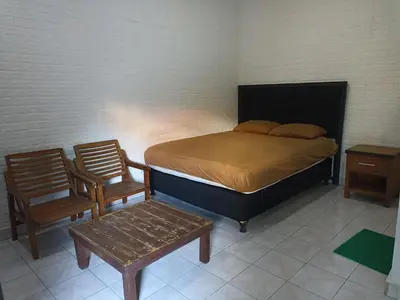 a bedroom with a bed and two chairs and a table at Tokomang Homestay in Legian