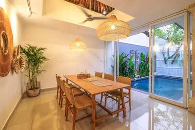 a dining room with a wooden table and chairs at Casa De Beji Seminyak in Seminyak