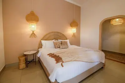 a bedroom with a large white bed and two lights at Casa De Beji Seminyak in Seminyak