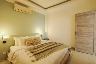 a bedroom with a large bed with a wooden door at Casa De Beji Seminyak in Seminyak