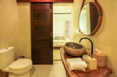 a bathroom with a sink and a toilet and a mirror at Casa De Beji Seminyak in Seminyak