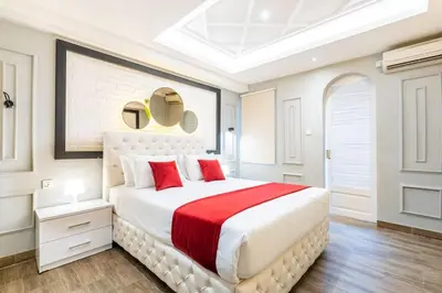 a white bedroom with a large bed with red pillows at Luxury Villa Belvedere Bali in Seminyak in Seminyak