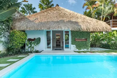 a villa with a swimming pool and a thatch roof at Villa Sukacita - Family Friendly 4BR Seminyak Eat Street 900m Walk To Beach in Seminyak