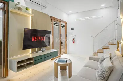 a living room with a tv on a wall at Calisee Villa by Kozystay - Denpasar in Seminyak