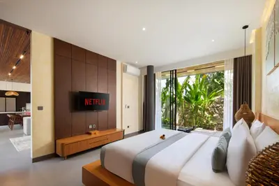 a bedroom with a large bed with a television on the wall at Oza Villa Canggu Managed by LEAD in Canggu