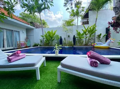 two beds on the grass in front of a swimming pool at Tranquil Family Villa Retreat in Umalas in Kerobokan